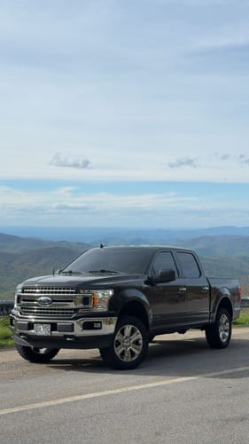 Reviewer's black Ford F150 with a 3-inch lift kit installed, parked on a road with a mountain view.