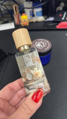 Customer holding a clear bottle of Vanilla At Eight! perfume with a wooden cap.