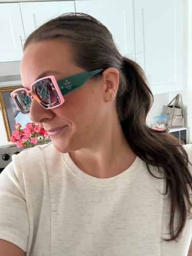 A reviewer's side profile wearing the color-block Deco Sunglasses with pink frames and green arms.