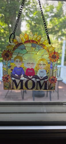 Customer's personalized sunflower suncatcher with a mom and two children hanging in a sunlit window.