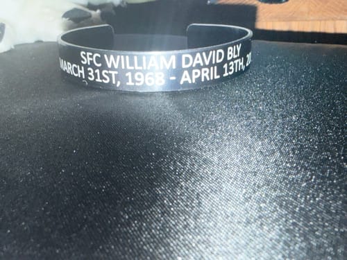 Customer's custom black bracelet showing the engraved name and dates on the outside.