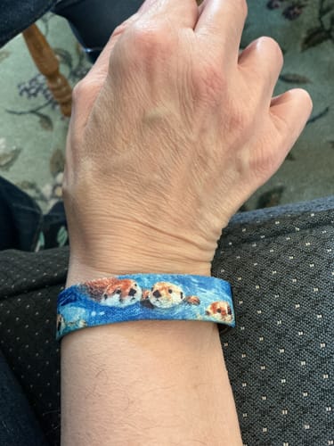 Customer's 'Water You Waiting For?' Bracelet on their wrist, featuring a playful blue otter pattern.