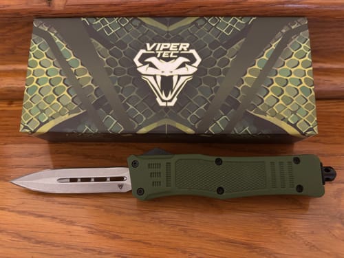 Reviewer's Small Green Phantom OTF knife with the blade deployed, shown on a wooden surface next to its box.