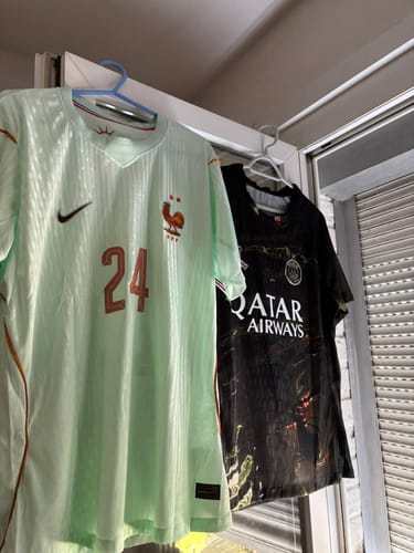 Photo d'un client montrant le maillot PSG x Jordan spécial édition noir, suspendu sur un cintre.