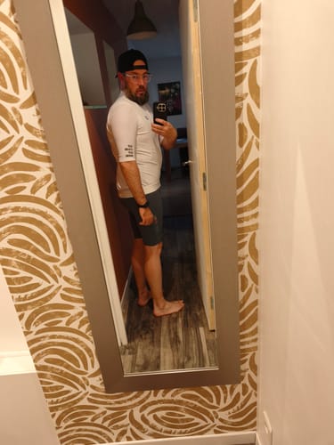 Reviewer showing the fit of the gray LIFTTINT 4.X BIB SHORTS from the side in a full-length mirror.