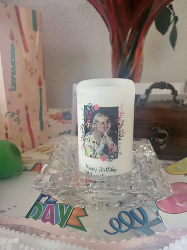 Rezensent zeigt die personalisierte Geburtstagskerze mit dem Foto einer Person in einem gläsernen Kerzenhalter.