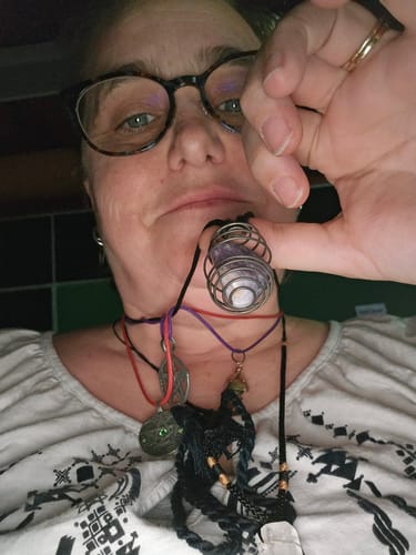 Reviewer showing their lepidolite tumble from the VIP Crystal Club worn in a silver-colored spiral cage necklace.