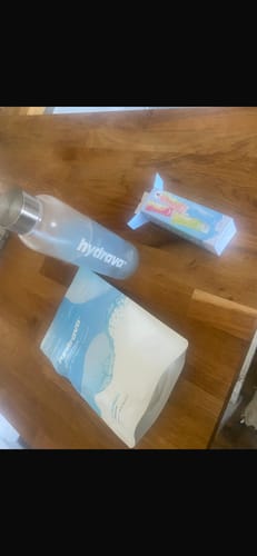 Customer's Electrolyte Salts sample pack, including a pouch and box, next to a water bottle on a wooden table.