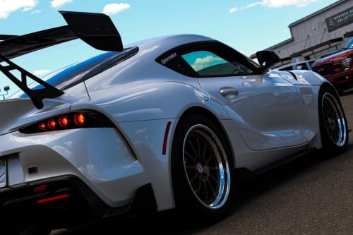 Reviewer's white sports car showing the bronze rims that match the 80Eighty® Bronze Valve Stem Caps.