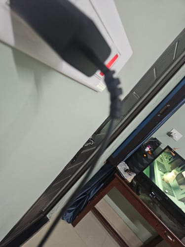Close-up of a customer's black Cable Protector on a charging cable plugged into a wall outlet.
