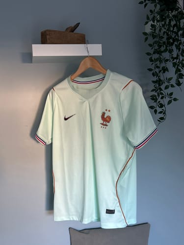 Client montrant le maillot France vert sur un cintre en bois.