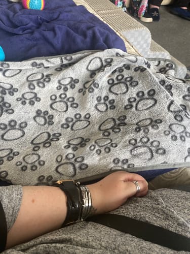 Close-up of a customer's grey Anti-Stress Blanket with a black paw print pattern.