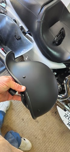 Customer holding the Polo Curve Flat Black helmet, with a motorcycle in the background.