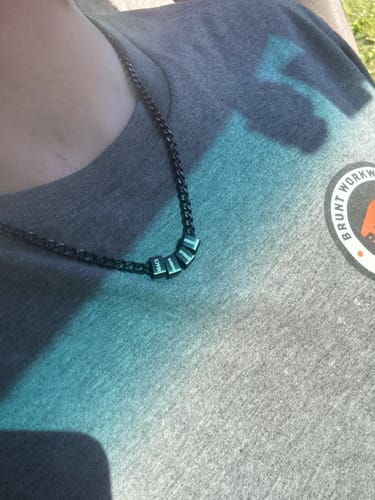 Customer wearing the black Legacy Necklace with several personalized beads against their grey shirt.