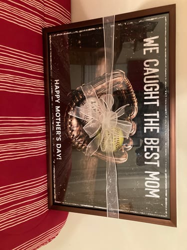 Customer's 'We Caught The Best Mom' poster in a dark frame, wrapped with a lovely white gift ribbon.