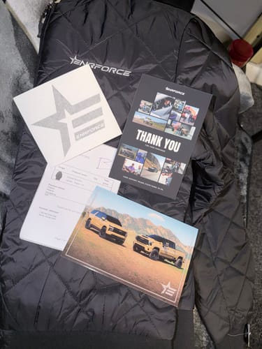 Customer's black quilted Ladies Bomber Jacket laid out with the thank you card and other included items.