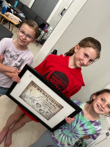 Customer shows three children holding the framed 'To My Daughter' personalized poster.