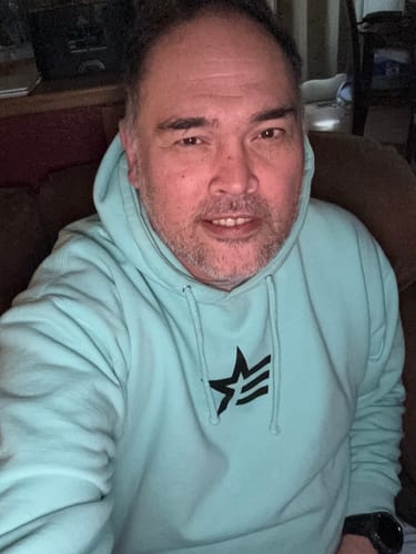 Reviewer taking a selfie while wearing a light-colored hoodie indoors.