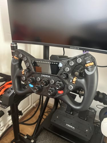 Customer's MOZA RACING KS Pro Steering Wheel mounted on a black sim racing rig in front of a monitor.