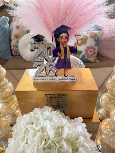 Customer's personalized 'Class of 2026' acrylic plaque, with a graduate figure, displayed on a decorative gold box.