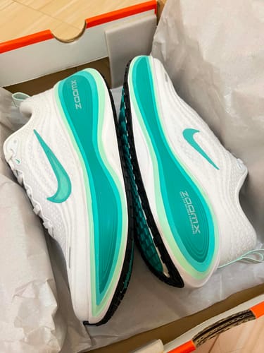 Customer's white and teal Nike Vomero Plus running shoes resting in the original shoebox, showing the sole.