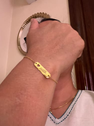 Customer wearing the Golden Personalised Cosy Heart Bracelet on their wrist, showing the engraved nameplate.