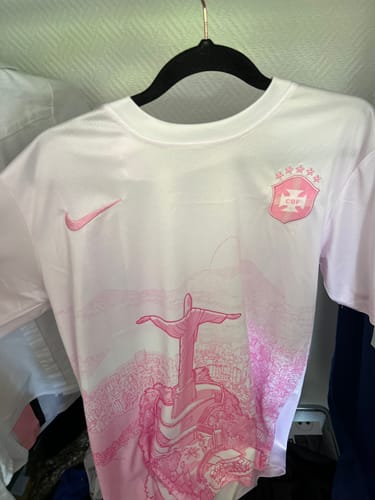 Client montrant le maillot concept Brésil blanc et rose suspendu sur un cintre noir.