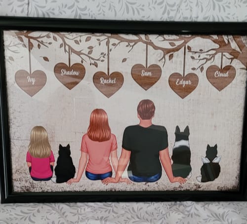 Customer's personalized poster of a family with pets sitting under a heart tree, displayed in a black frame.