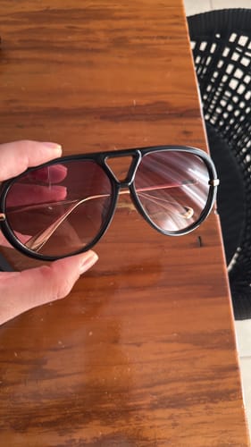 Cliente segurando os Óculos Veneza com armação preta grande e lentes em degradê.