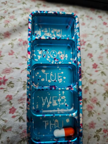 Reviewer's open Weekly Case in a cherry blossom pattern, showing labeled compartments with one pill inside.