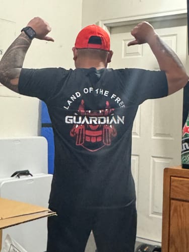 Reviewer from behind wearing the black Guardian Tee, flexing to show the back graphic.