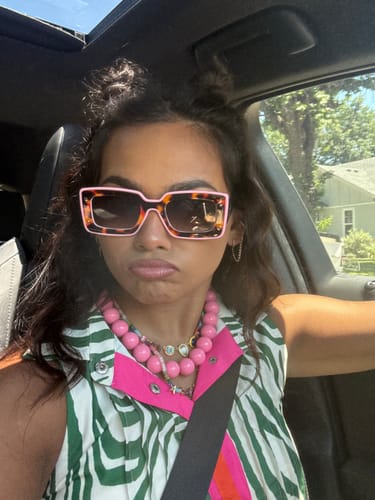 Reviewer wearing the Deco Sunglasses, showing off the stylish pink and tortoiseshell color-block frame in a car.