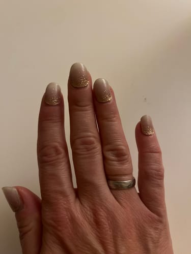 Hand einer Kundin, die ihre 'Babyboomer Nude Sparkle' UV-Gel-Maniküre nach fast drei Wochen Tragezeit zeigt.