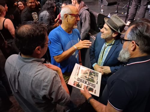 Customer wearing a blue Simple Record T-Shirt while talking to people at a concert.