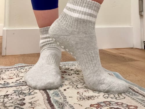 Reviewer wearing the gray Dual-Direction Grip Stripes socks and turning one foot to show the inner grippers.