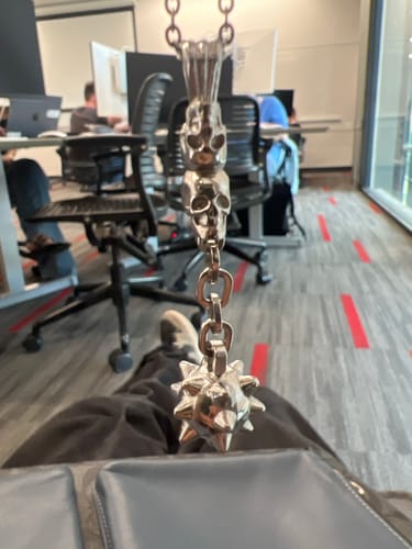 Customer holding the Free Exclusive 1M Item, a silver pendant with stacked skulls and a spiky mace.