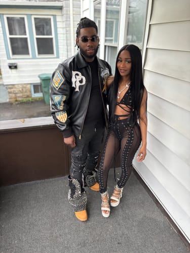Customer and a companion standing together on a porch, showcasing their new black outfits.