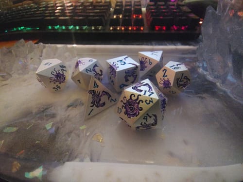 Customer's silver and purple Monster Manual dice set displayed in a tray, showing the intricate monster designs.