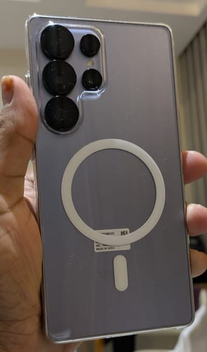 A customer's hand holds a Samsung phone inside the clear Anti Yellow Magsafe case, showing the back.