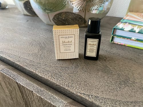 Recensent toont de verpakking van de Istanbul Golden Hour Parfum Sample en een flesje shampoo op een dressoir.