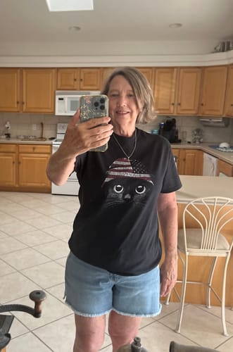 Customer taking a selfie in her black t-shirt featuring a cat wearing a patriotic hat.