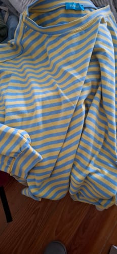 Nahaufnahme des gelb-blau gestreiften SOUL STRIPES Pullovers eines Kunden auf einem Holzboden.
