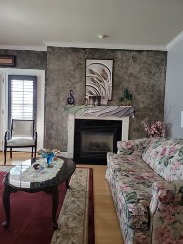 Customer's 3D Minimalist Wheat Wall Art hanging on a dark textured wall above a fireplace in a living room.