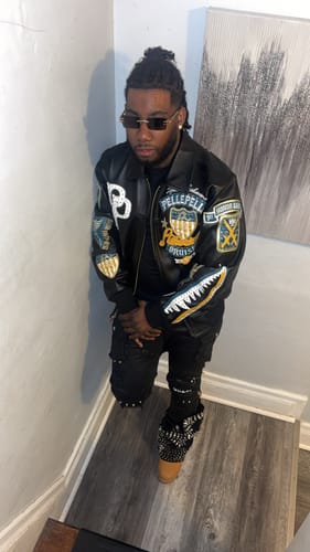 Customer posing on a staircase, giving a full view of their decorated black jacket, pants, and studded boots.