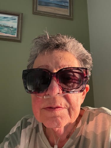 Reviewer wearing the large, floral frame fit over sunglasses indoors.