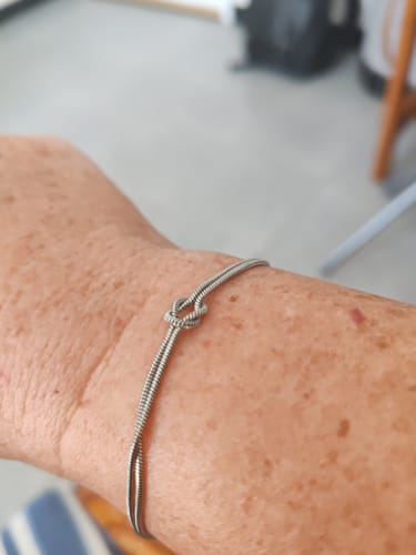 Customer wearing the silver Forever Knot Bracelet on their wrist, showing the knot detail.