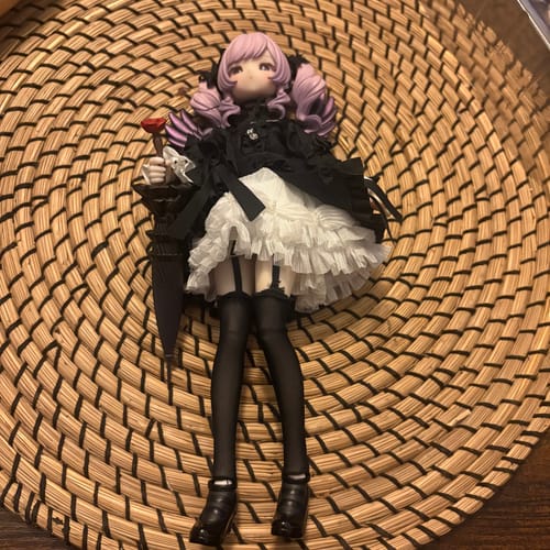 Customer's Dream-Devourer action figure with purple hair and a black and white dress, posed on a woven surface.