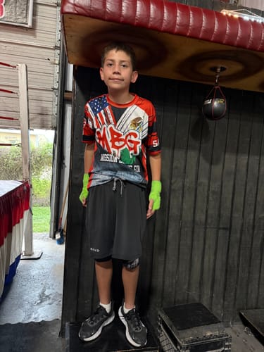 Customer in a gym wearing the black Philippians 4:13 'Strength in Christ' Youth Performance Shorts.