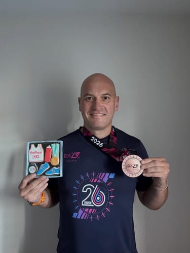 Customer holds the Running Biscuit Box, showing the personalized biscuits, while wearing his marathon medal.