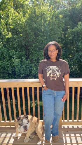 Reviewer wearing the brown Whiskey English Bulldog T-shirt on a deck, standing next to their real English bulldog.